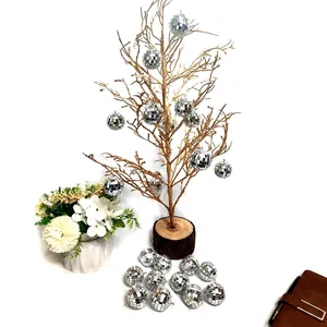 Set of small silver mirror disco balls hanging on a decorative golden tree for party