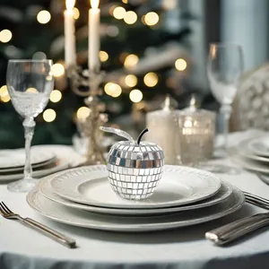 Verspiegelter Apfel-Discokugel-Ornament auf festlichem Tisch mit Bokeh-Lichtern