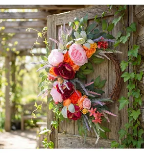 Close-up of vibrant pink and orange peony wreath with lavender and greenery on a rustic door