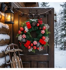 Detailweergave van een feestelijke kerstkrans op een besneeuwde rustieke deur.