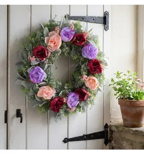 Vibrant three-color peony floral wreath hanging on a white rustic wooden farmhouse door