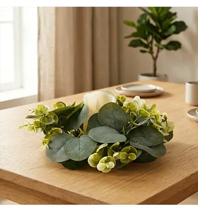 Detail view of a eucalyptus leaf candle ring with white candle on a wooden table.