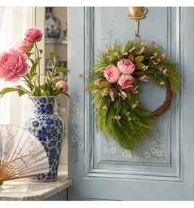 Dettaglio di una rigogliosa ghirlanda di peonie rosa appesa a una porta blu.
