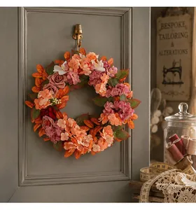 Dettaglio di una ghirlanda autunnale con ortensie e rose su una porta grigia vintage