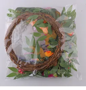 Detail view of artificial pink orange peony wreath stored in a clear plastic bag