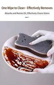 Close-up of cute cat-shaped 3-layer cleaning sponge wiping dark sauce off a white plate