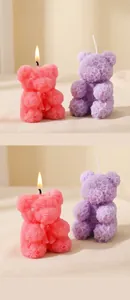 Dettaglio di una candela profumata a forma di orso rosa accesa su un vassoio d'oro