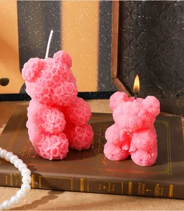 Gros plan détaillé de deux bougies parfumées en forme d'ours rose sur un vieux livre