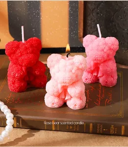 Bougies parfumées artisanales en forme d'ours rose sur un fond de livre vintage