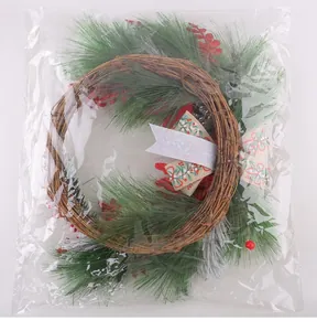 Christmas wreath with pine branches and red berries shown inside its clear packaging bag