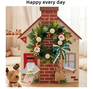 Corona de Navidad festiva con figuras de Papá Noel sobre fondo de casita de juguete