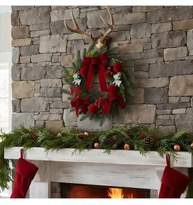 Christmas wreath with wine red velvet bows and reindeer hanging on a stone fireplace