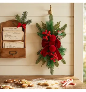 Festive burgundy velvet bow Christmas teardrop swag with red berries hanging on a wall