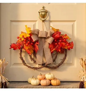 Autumn maple leaf wreath with red berries and burlap bow hanging on a cream front door.