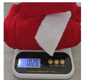 Gros plan de la robe de Noël en peluche rouge et blanche sur une balance pesant 182,6 g.