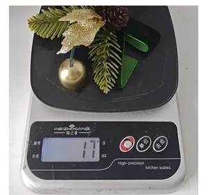 Ornement de nœud de Noël avec cloche et aiguilles de pin pesant 17 grammes sur balance