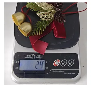 Vue détaillée d'un pendentif de Noël avec nœud et cloches pesant 24g sur une balance de cuisine