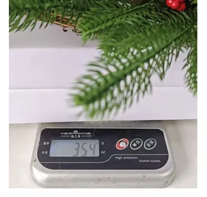 Detail shot of a Christmas wreath with red berries being weighed at 354g on a scale