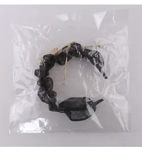 Détail d'un serre-tête gothique en maille noire avec squelette sous sachet clair.