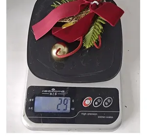 Détail d'un nœud papillon de Noël de 29g avec cloche posé sur une balance de cuisine