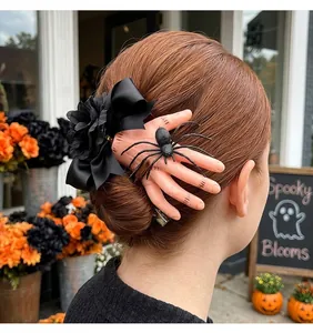 Detalle de la pinza para el pelo de Halloween con mano cortada, lazo negro y araña.