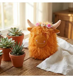 Primo piano di un peluche di mucca delle Highlands arancione con fascia di fiori rosa