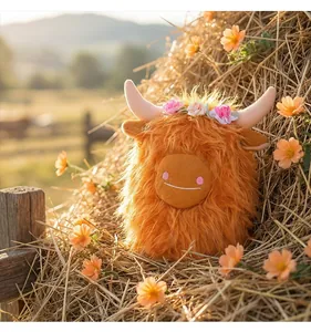 Adorabile peluche di mucca Highland arancione con ghirlanda su sfondo di fieno