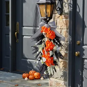 Handmade Halloween skeleton swag wreath with orange flowers and striped bow for porch decor