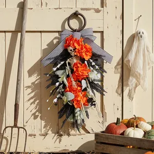 Halloween skeleton teardrop wreath with orange flowers and striped bow on wooden door