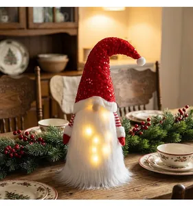 Detailansicht eines festlichen Weihnachtswichtels mit roter Paillettenmütze und LED-Licht