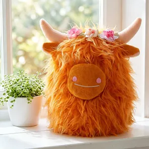 Simpatico peluche di mucca Highland arancione con corona di fiori sul davanzale