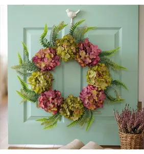 Decorative artificial hydrangea and fern floral wreath displayed on a green door