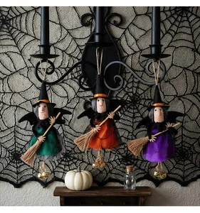 Detail van drie hangende Halloween-hekshangers met bezems en kleine gouden bellen.