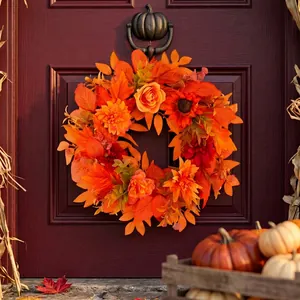 Ghirlanda autunnale con foglie d'acero arancioni e dalie su una porta di legno scuro