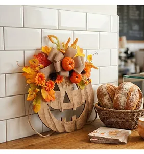 Decorative wooden Halloween pumpkin door hanger with autumn leaves and burlap bow
