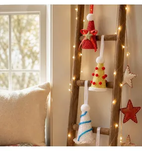 Set van drie kerstmutsen met pailletten in kegelvorm aan een rustieke houten ladder