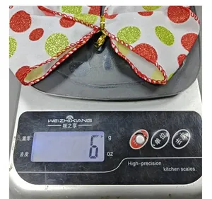 Detailed view of a red and green polka dot Christmas bow weighing 6 grams on a scale