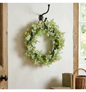 Detailansicht eines künstlichen Frühlingskranzes mit weißen Blüten am Wandhaken