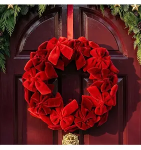 Detalle de una corona de Navidad con lazos de terciopelo rojo en una puerta