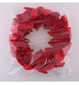Detalle de corona de Navidad de terciopelo rojo con lazos en bolsa de plástico.