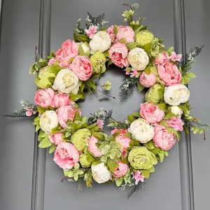 Detailansicht eines Pfingstrosenkranzes in Rosa und Creme an einer grauen Tür.
