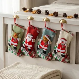 Set of four colorful Christmas stockings with 3D Santa and reindeer characters hanging on bed.