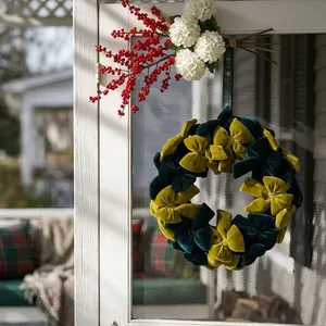 Corona de Navidad artesanal con lazos de terciopelo verde y oro para colgar en la puerta.