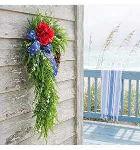 Couronne patriotique avec roses rouges et ruban étoilé sur le mur d'une maison de plage en bois