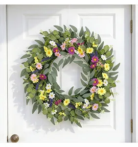 Lebendiger Frühlingskranz mit Wildblumen und grünen Blättern an einer weißen Haustür