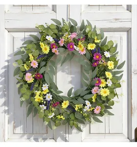 Frühlingskranz mit bunten Wildblumen und Eukalyptusblättern auf einer weißen Holztür