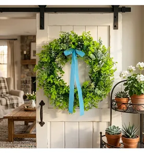Green leaf wreath with blue ribbon hanging on a white wooden door in farmhouse decor