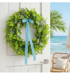 Detailed view of lush green artificial wreath with long light blue velvet ribbon on door