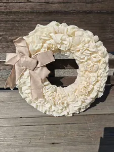 Detail van een crème kanten krans met een rustieke strik van natuurlijk jute.
