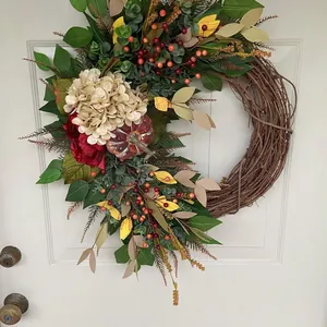 Vue détaillée d'une couronne d'automne avec hortensias et citrouille sur une porte